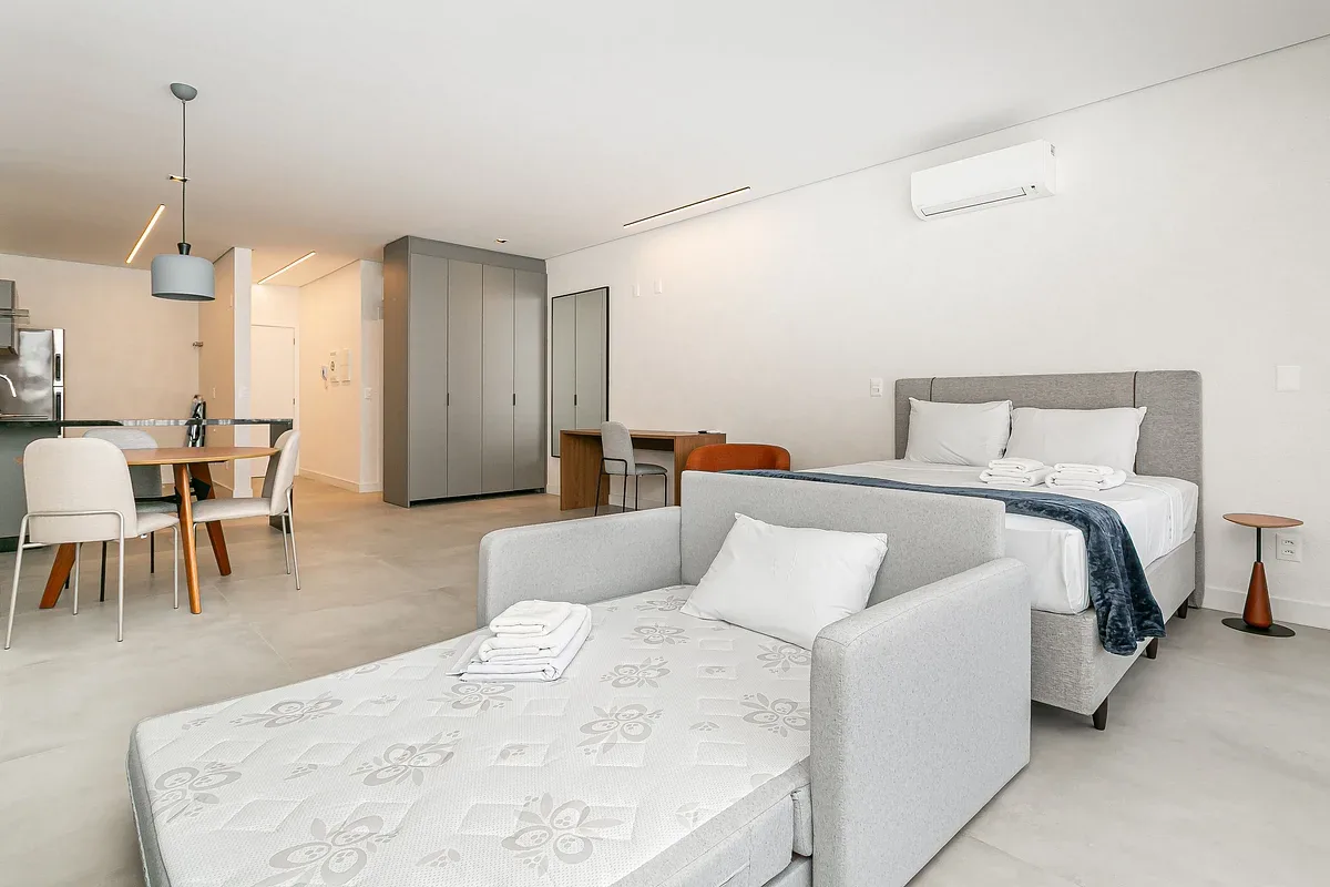 A bright bedroom with a bed and a daybed beside a small dining area.