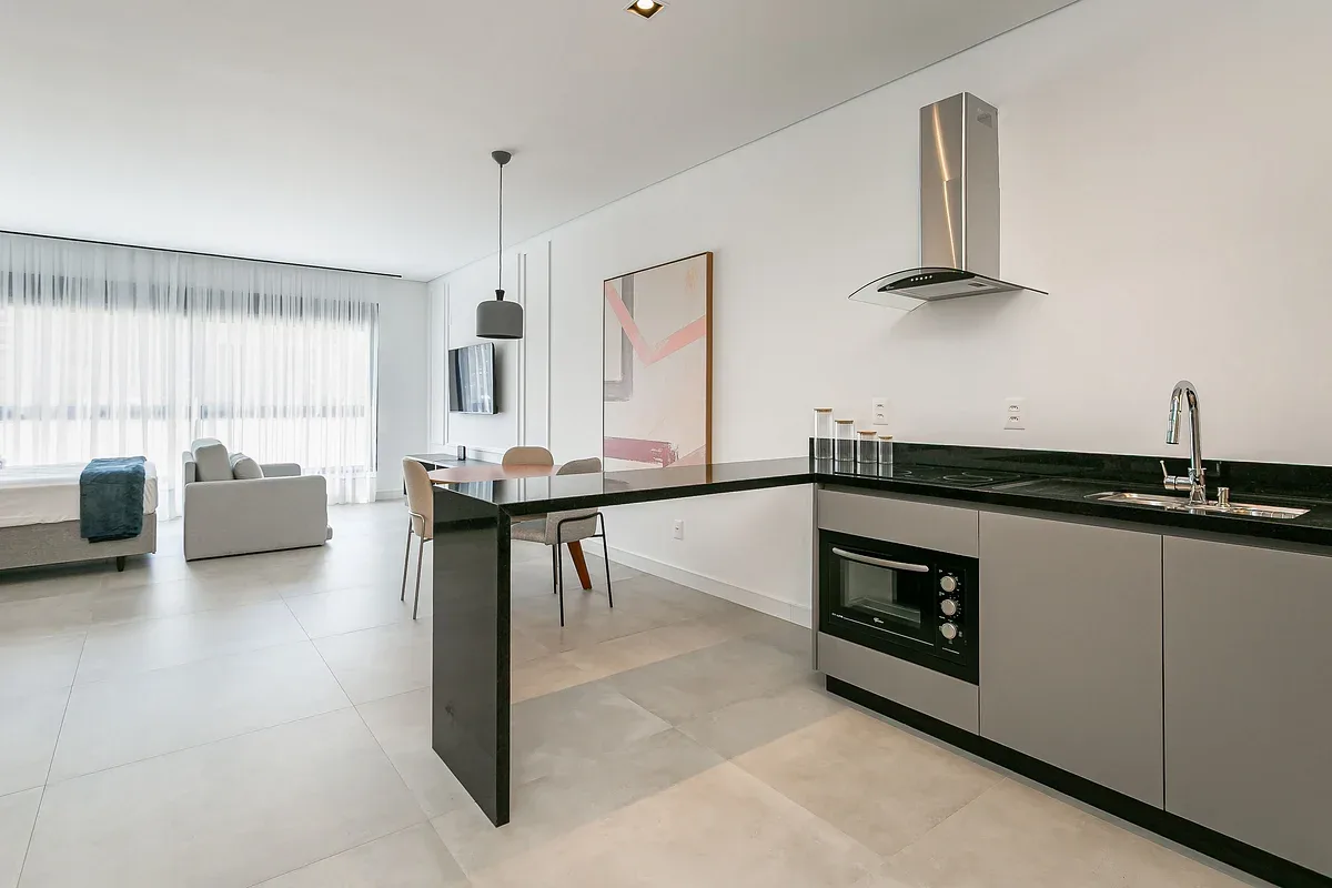 An open-plan kitchen and living area with a dining counter and large windows.