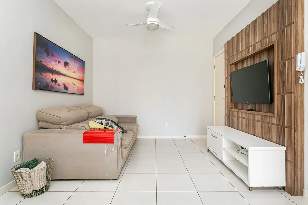 A living room with seating, two televisions, and a white media console.