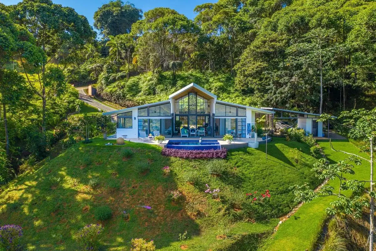 Una casa moderna se encuentra entre césped verde y árboles frondosos.