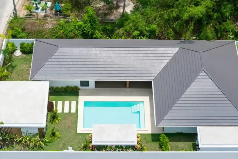 An aerial view shows a house beside a rectangular swimming pool and garden.