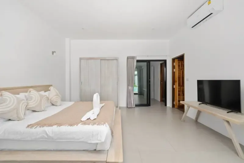 A bright bedroom with a bed and television.