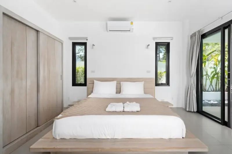 A bedroom with a large bed, built-in wardrobes, and glass doors opening outside.