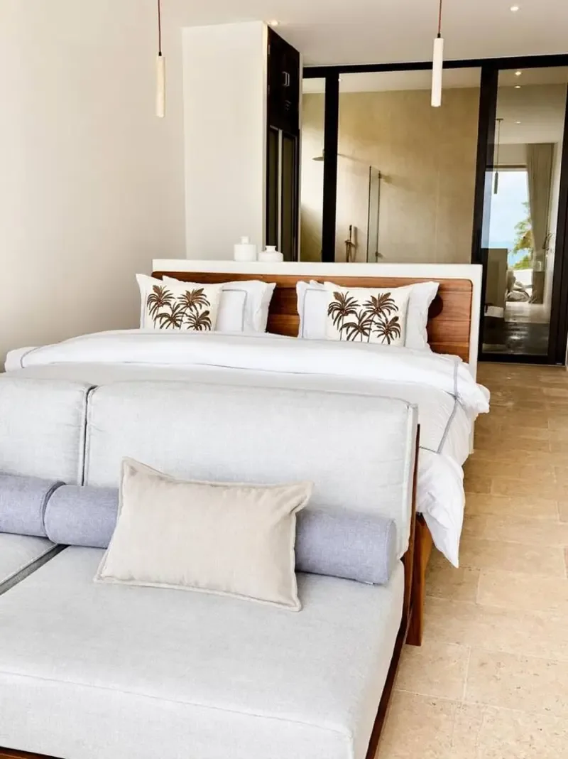 A bedroom with a bed and a light-colored seating area in the foreground.