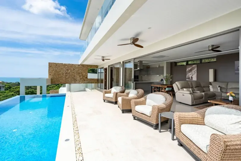 Una sala de estar moderna se abre a una terraza junto a una piscina.