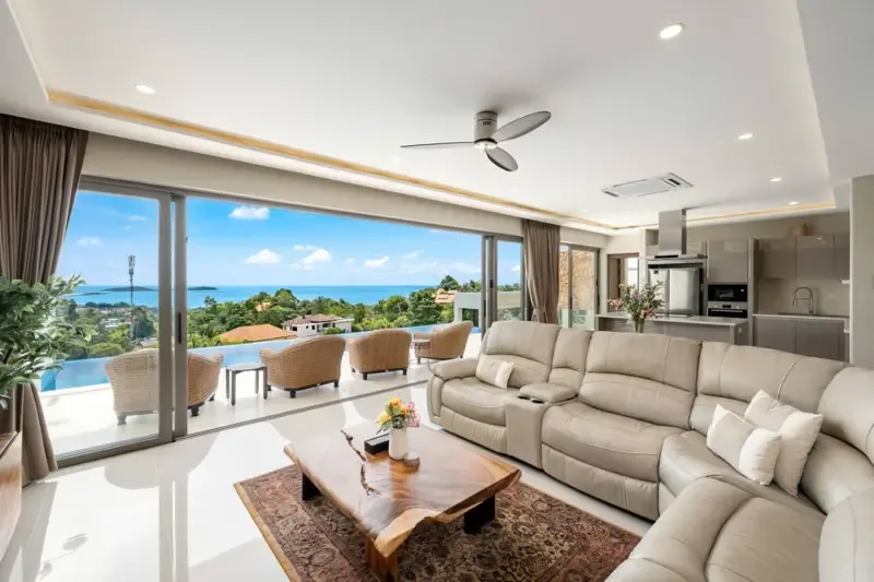 Una sala de estar luminosa con asientos y grandes ventanales con vistas al mar.