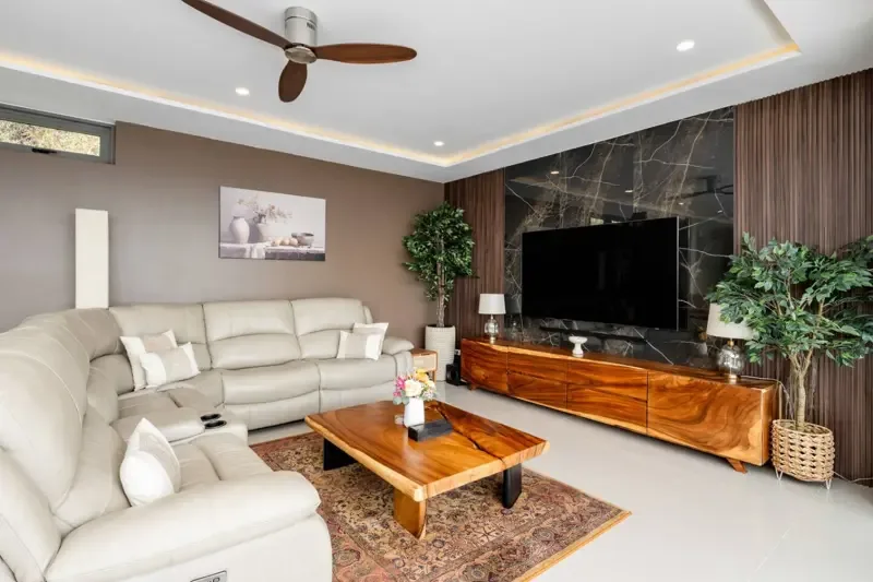 Una sala de estar con asientos claros, una mesa de centro de madera y un televisor.