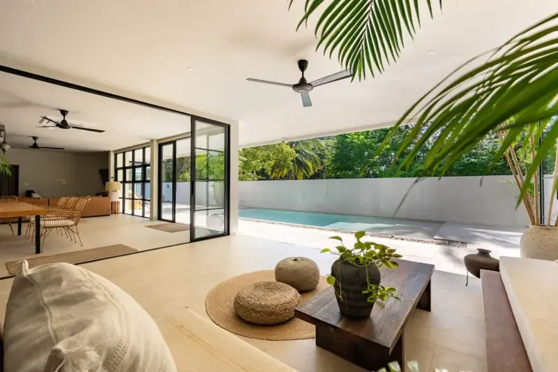 An open living area looks out onto a patio and swimming pool.