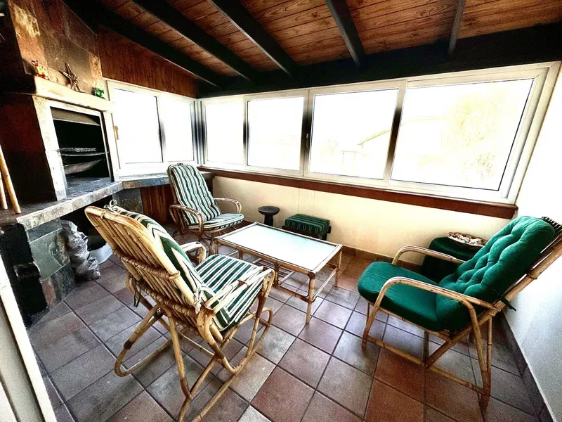 Un solárium con asientos acolchados alrededor de una mesa baja y amplias ventanas.