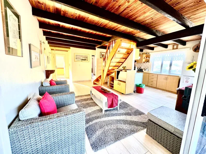 Una sala de estar con asientos de mimbre, una mesa de centro y una escalera.