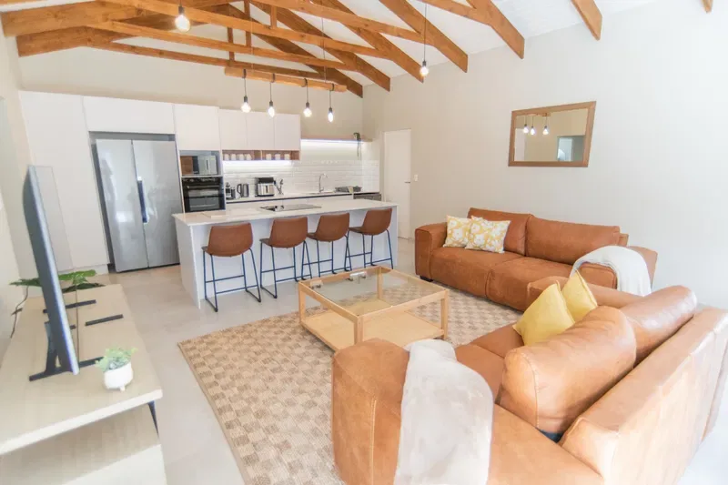 A bright open-plan living room and kitchen with a breakfast bar and seating.