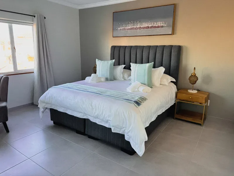 A bedroom with a neatly made bed and a window with curtains.