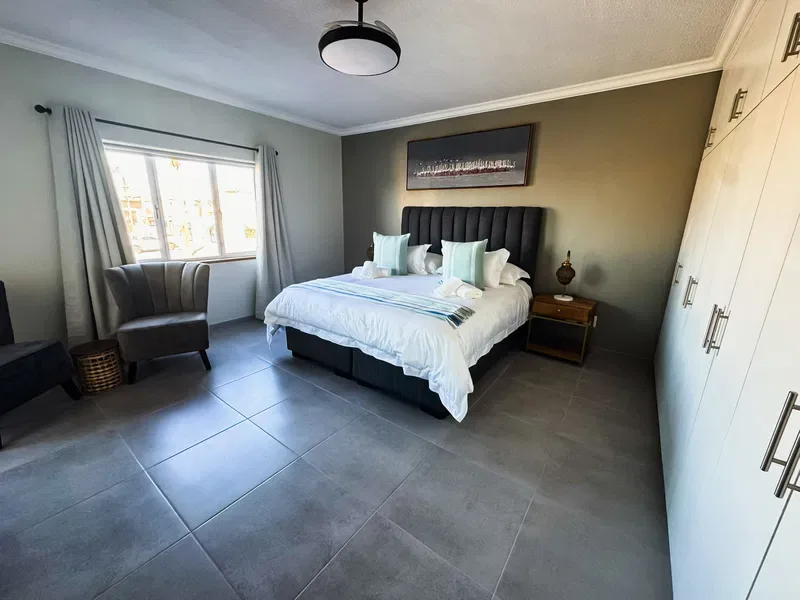 A bedroom with a made bed, a window, and a wardrobe.
