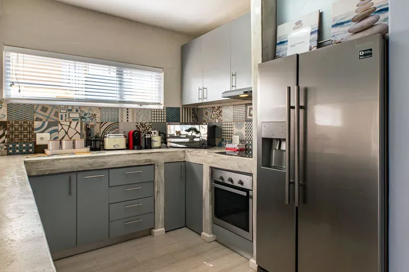 Una cocina moderna con gabinetes grises, salpicadero estampado y electrodomésticos de acero inoxidable.