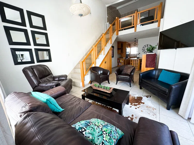 A living room with seating, a coffee table, and a staircase leading to an upper level.