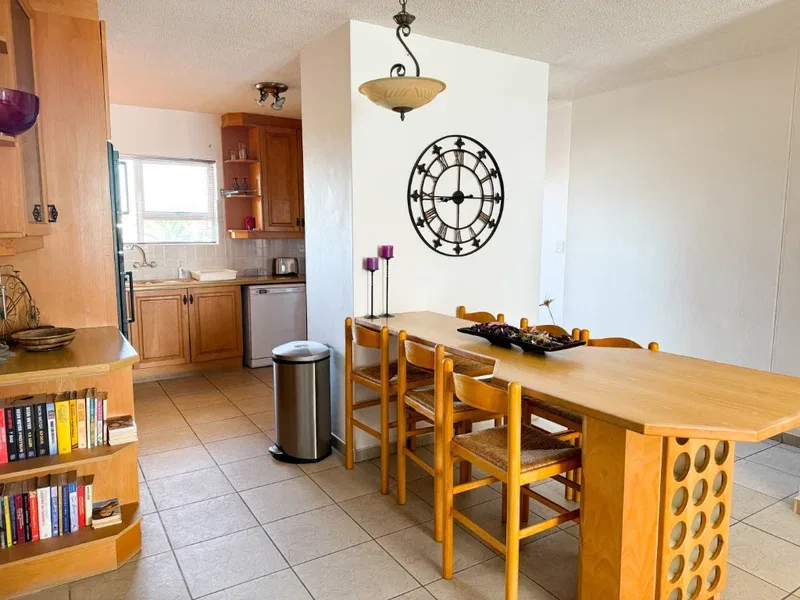 A dining area with a long wooden table beside an open kitchen.