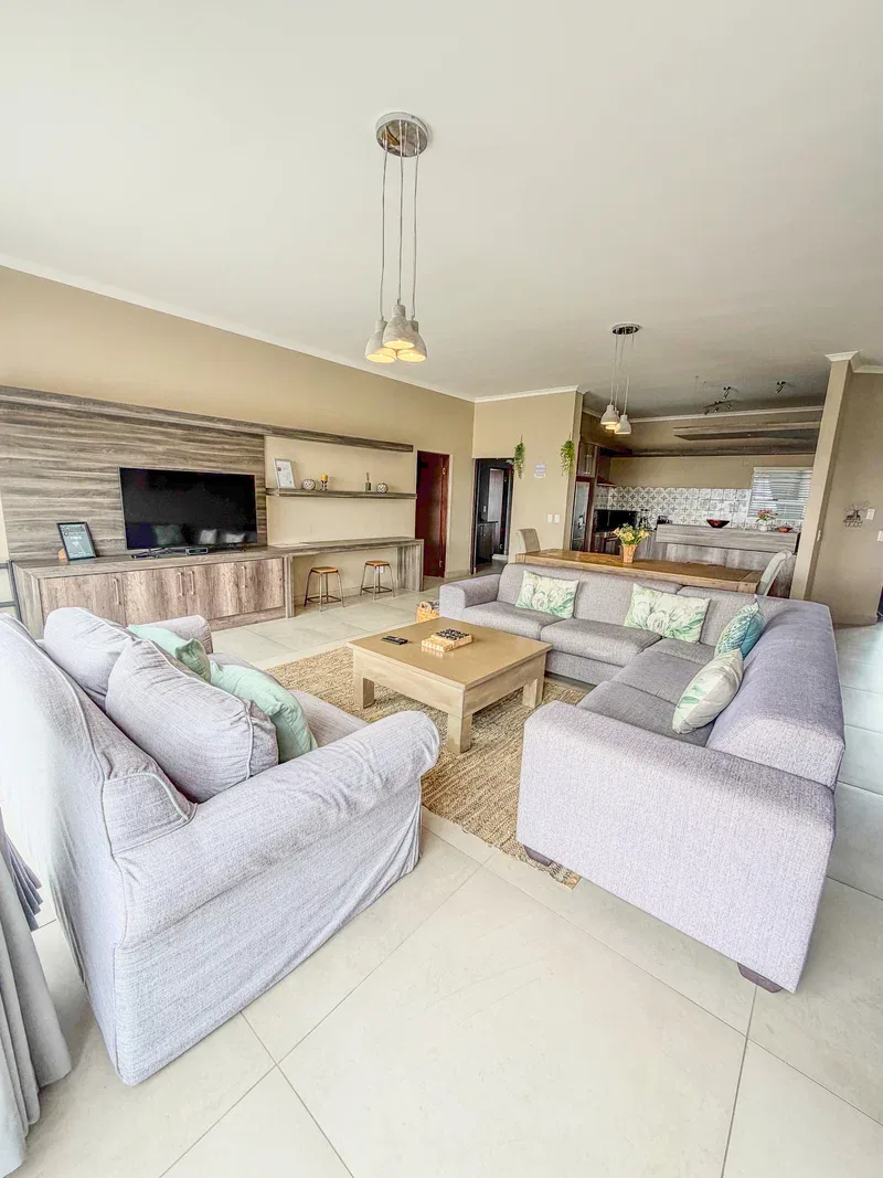 A spacious living room with light seating arranged around a wooden coffee table.