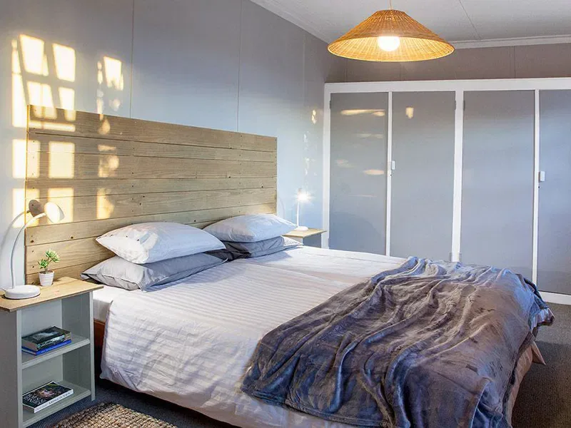 A bedroom with a large bed, bedside tables, and sliding closet doors.