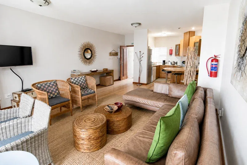 A living room with seating, a television, and an open kitchen area.