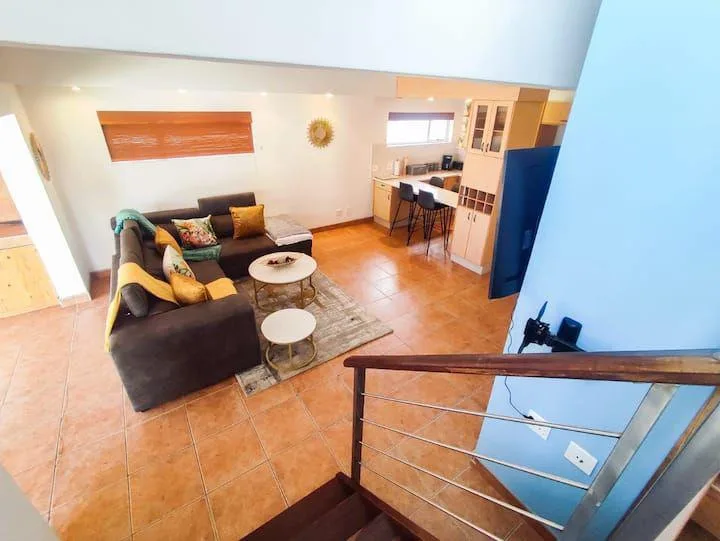 Una sala de estar con asientos y una pequeña barra de comedor bajo una escalera.