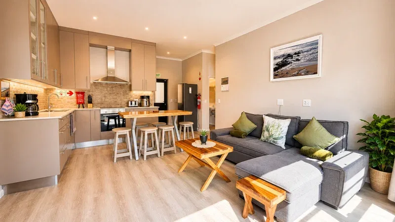An open-plan living room and kitchen with a dining counter and gray seating.