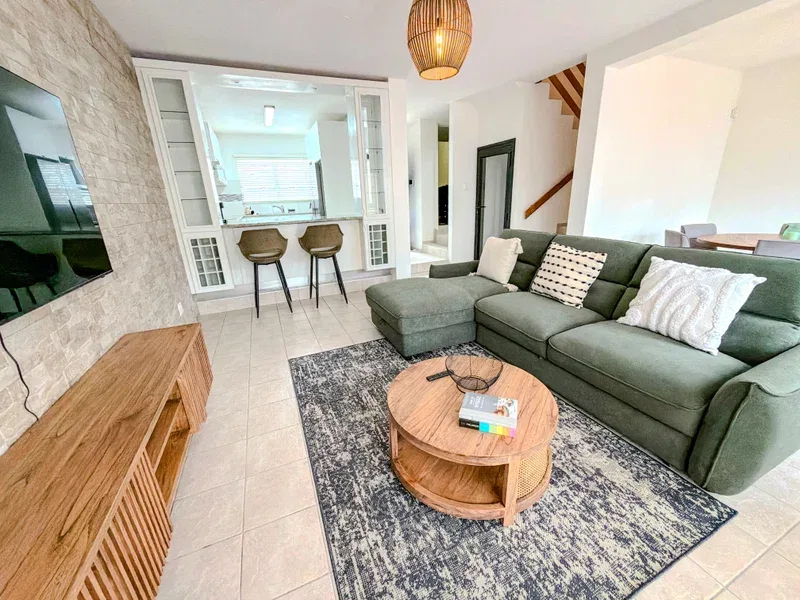 A living room with green seating, a round coffee table, and a television.