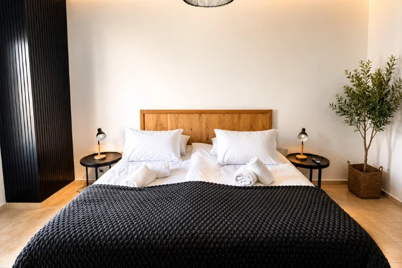 A bedroom with a neatly made bed and a potted plant beside it.