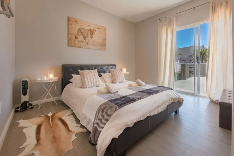 Un dormitorio con una cama tendida y cortinas junto a una puerta de vidrio.