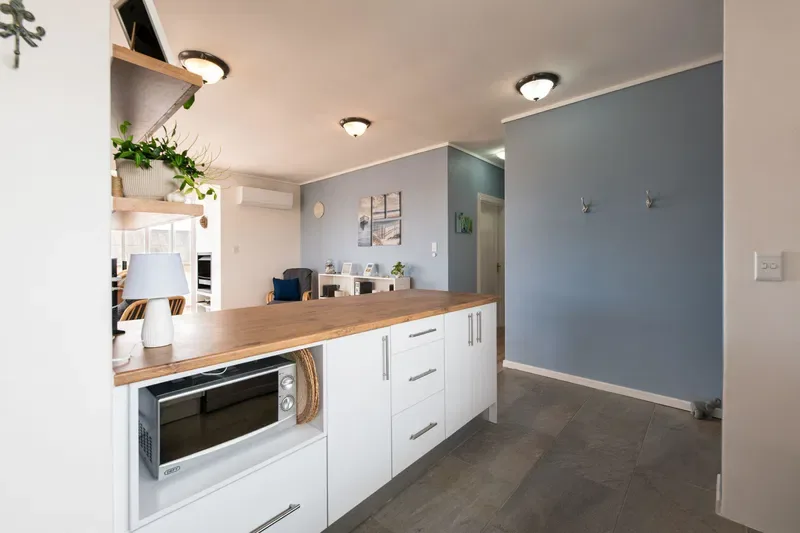 Una cocina luminosa con encimera de madera y gabinetes blancos.