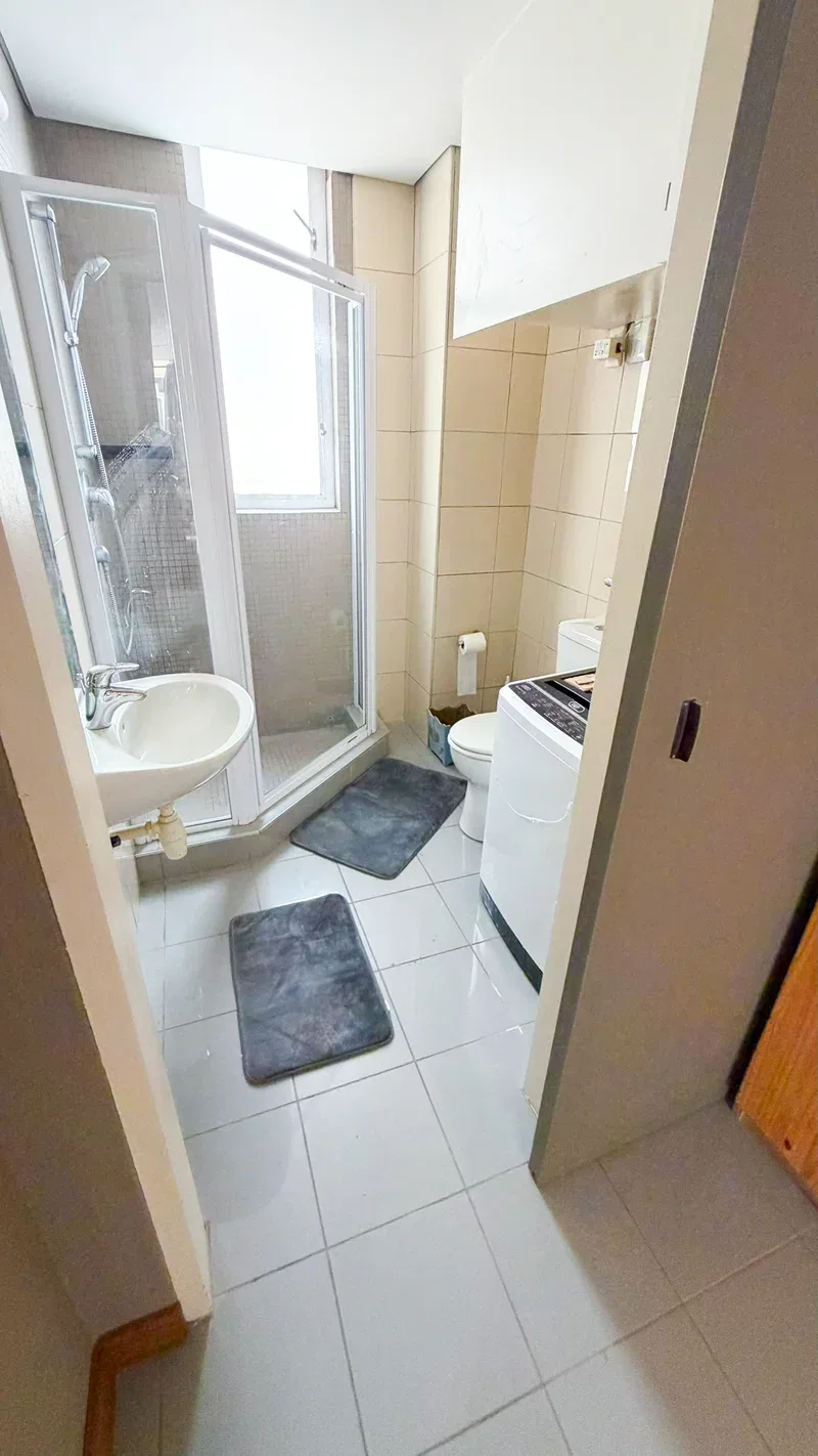 Un baño compacto con lavabo, inodoro y ducha con mampara de vidrio.
