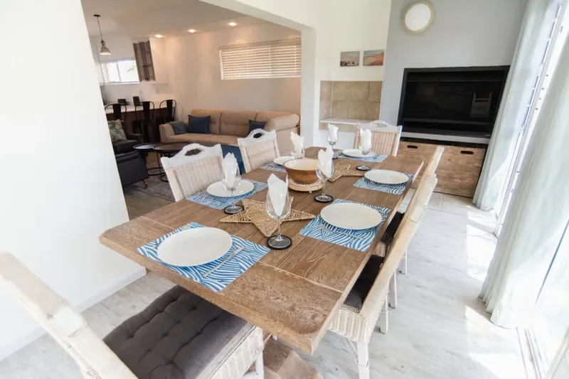 Comedor con una mesa de madera preparada con platos y manteles individuales.