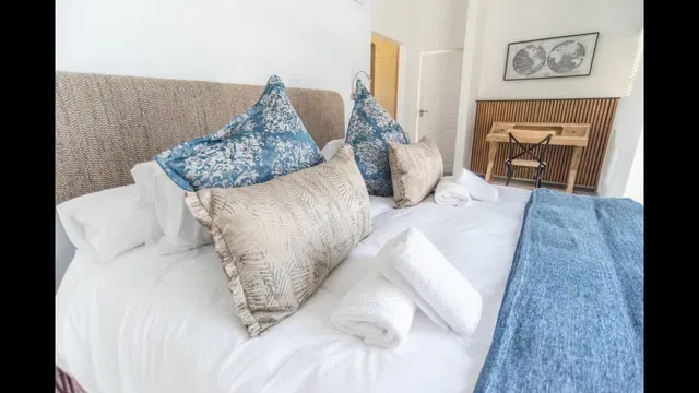 Una cama bien hecha con almohadas estampadas y toallas dobladas.