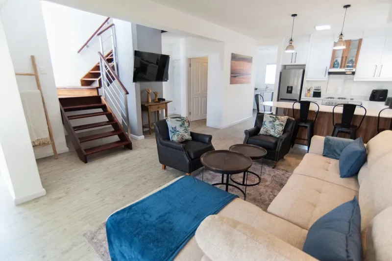 Una sala-comedor de espacio abierto con asientos junto a una cocina y una escalera.