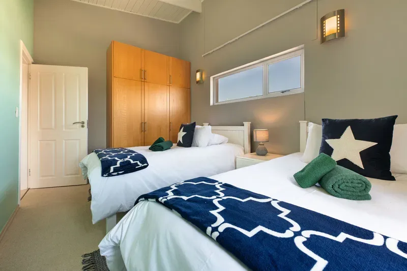 Un dormitorio con dos camas vestidas con ropa de cama blanca y mantas estampadas azul marino.