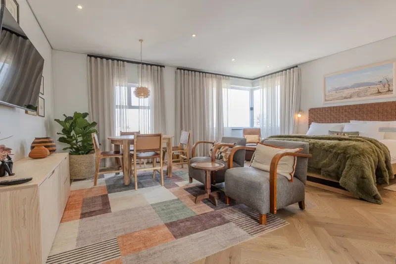 A bedroom and sitting area with a dining table beside the windows.