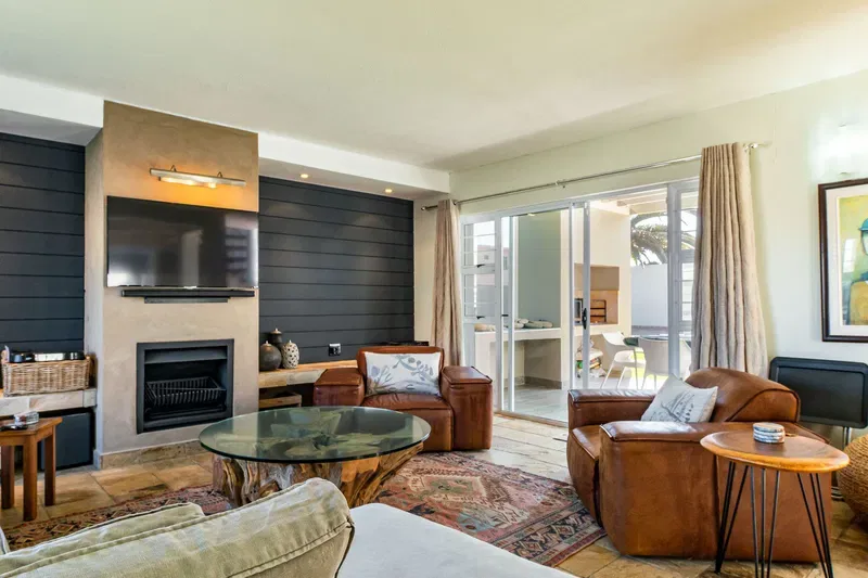A living room with seating arranged around a fireplace and television.