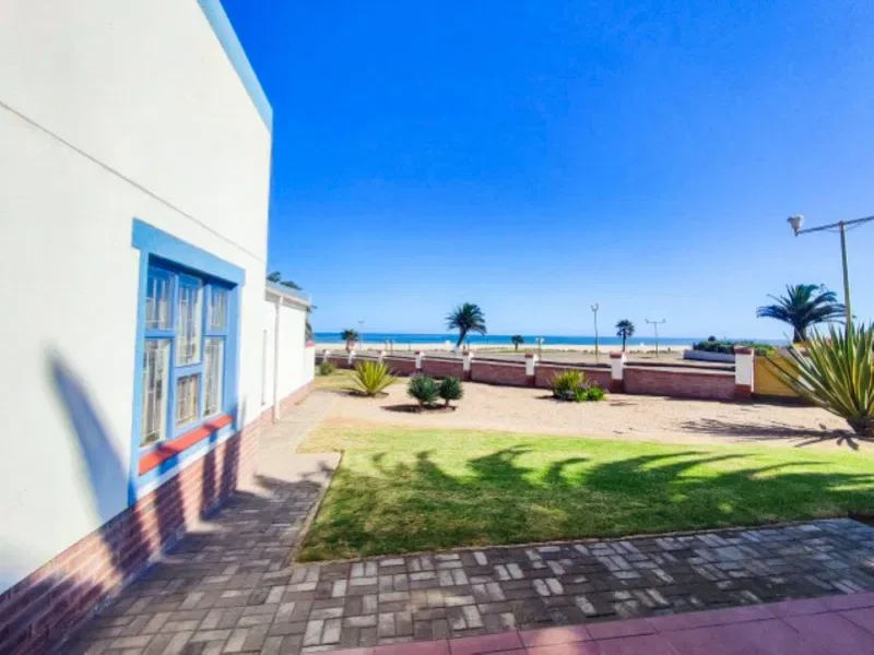 Un patio junto al mar con un sendero pavimentado, césped y vistas al océano.
