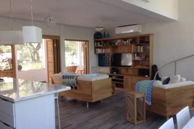 Una sala de estar con asientos de madera, un televisor y una gran estantería.