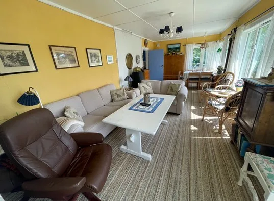 A living room with seating around a white coffee table and dining area by the windows.