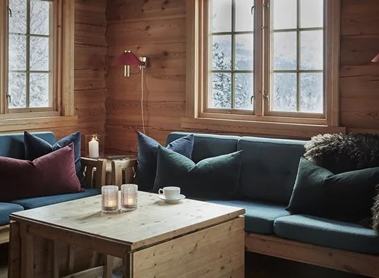 Una sala de estar con paneles de madera y asientos junto a grandes ventanas.