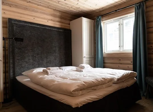Un dormitorio con una cama, toallas dobladas y una ventana.