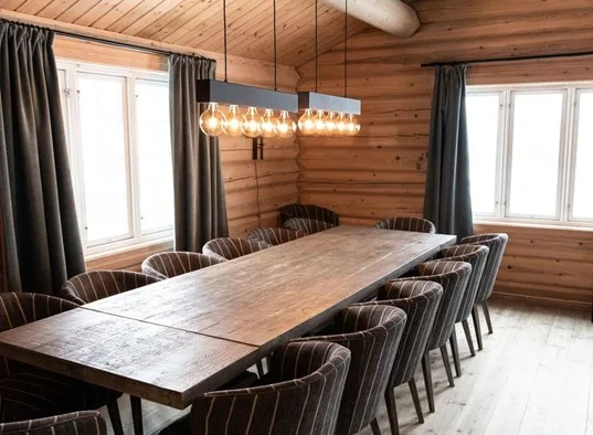 Comedor de madera con una mesa larga y asientos tapizados.
