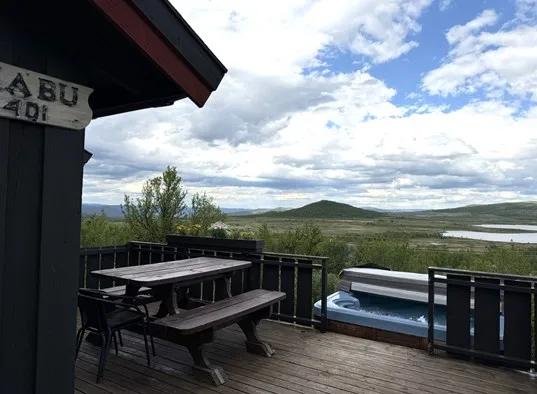 Una terraza con asientos de picnic da a una bañera de hidromasaje y al campo abierto.