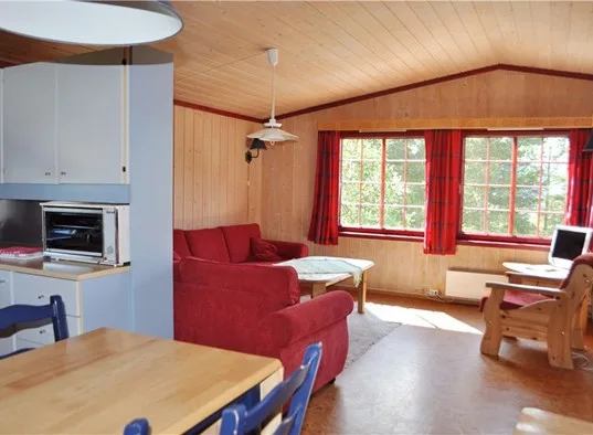 Una sala con paneles de madera, asientos rojos y ventanales.