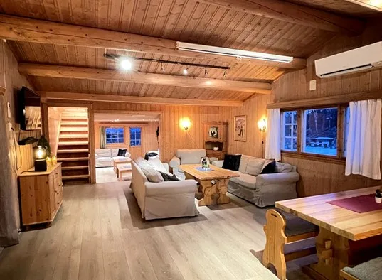 Sala de estar con paredes de madera y asientos alrededor de una mesa de centro.
