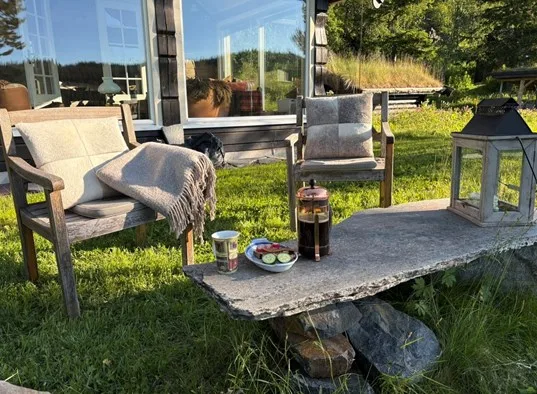 Outdoor seating beside a cabin, with a low stone table and garden lantern.
