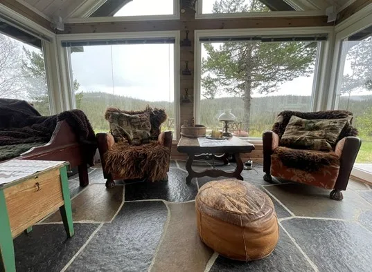 A sunroom with seating arranged around a low table and a round ottoman.
