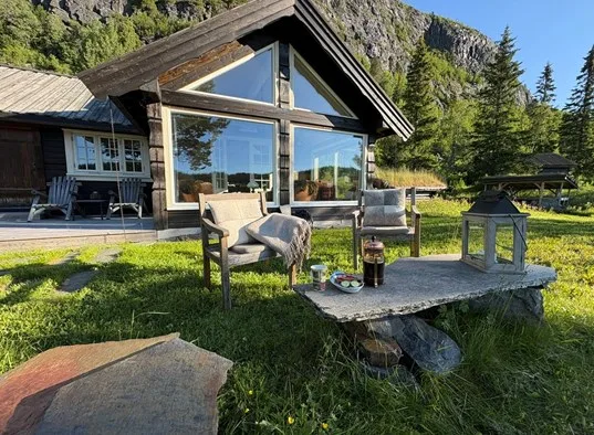 A cabin patio with outdoor seating and a low table beside large windows.