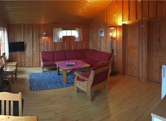 Una sala de estar con paneles de madera y asientos alrededor de una mesa de centro.