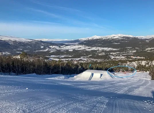Un paisaje montañoso nevado domina una pista de esquí acondicionada.